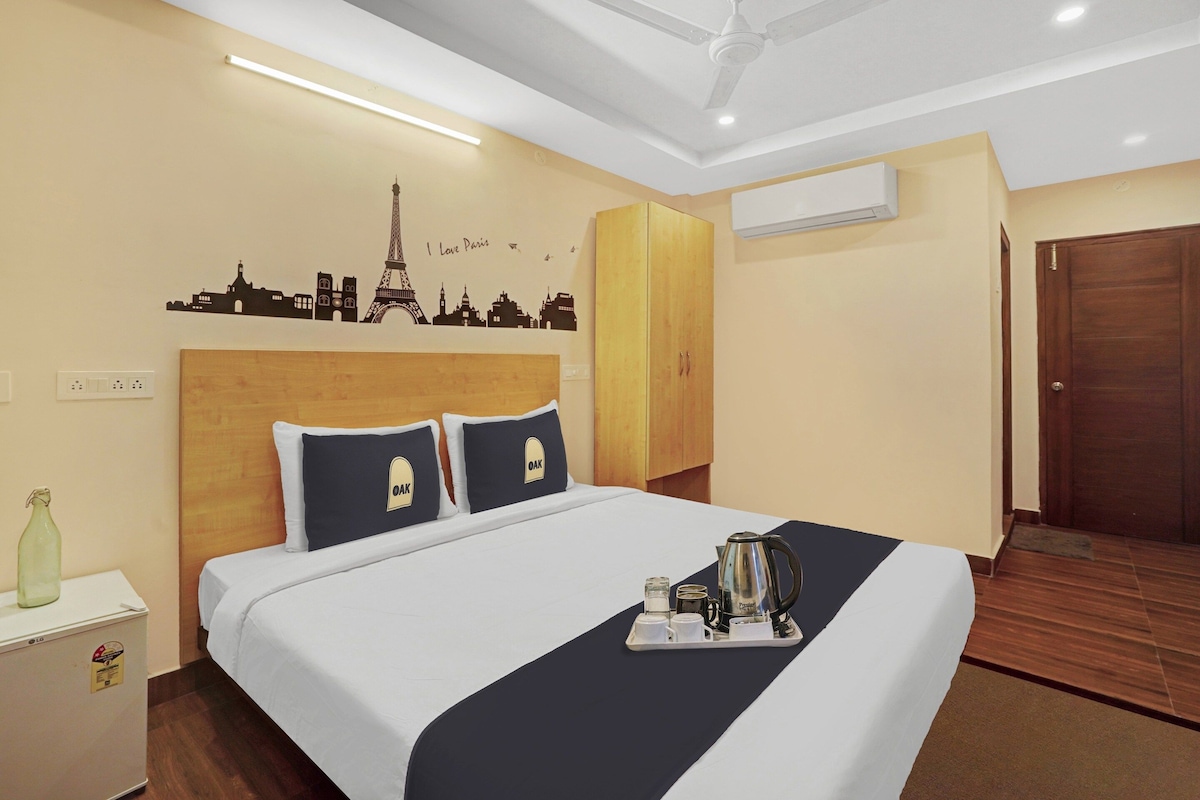 Habitación de hotel con cama, mesita de noche, aire acondicionado de pared y una puerta.