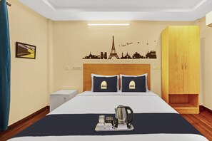 Una camera d'albergo con un letto, un comodino, un armadio e un adesivo murale raffigurante monumenti parigini.