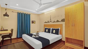 Une chambre d’hôtel équipée d’un lit, d’un bureau, d’une chaise, d’une armoire et d’un ventilateur de plafond.