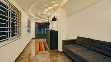 Un intérieur moderne avec un plafond incurvé, un canapé, un tapis coloré et un coin cuisine.