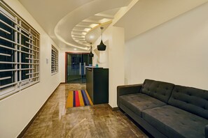 Un interno moderno con soffitto curvo, un divano, un tappeto colorato e una zona cucina.