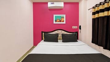 Una habitación con una cama, aire acondicionado de pared, un cuadro enmarco, un teléfono y una cortina.