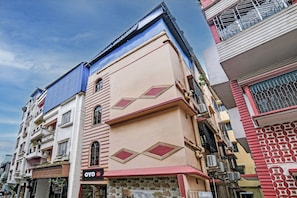 Un edificio de varios pisos con una mezcla de estilos arquitect ónicos, destacando un techo azul y una fachada beige con patrones geométricos.