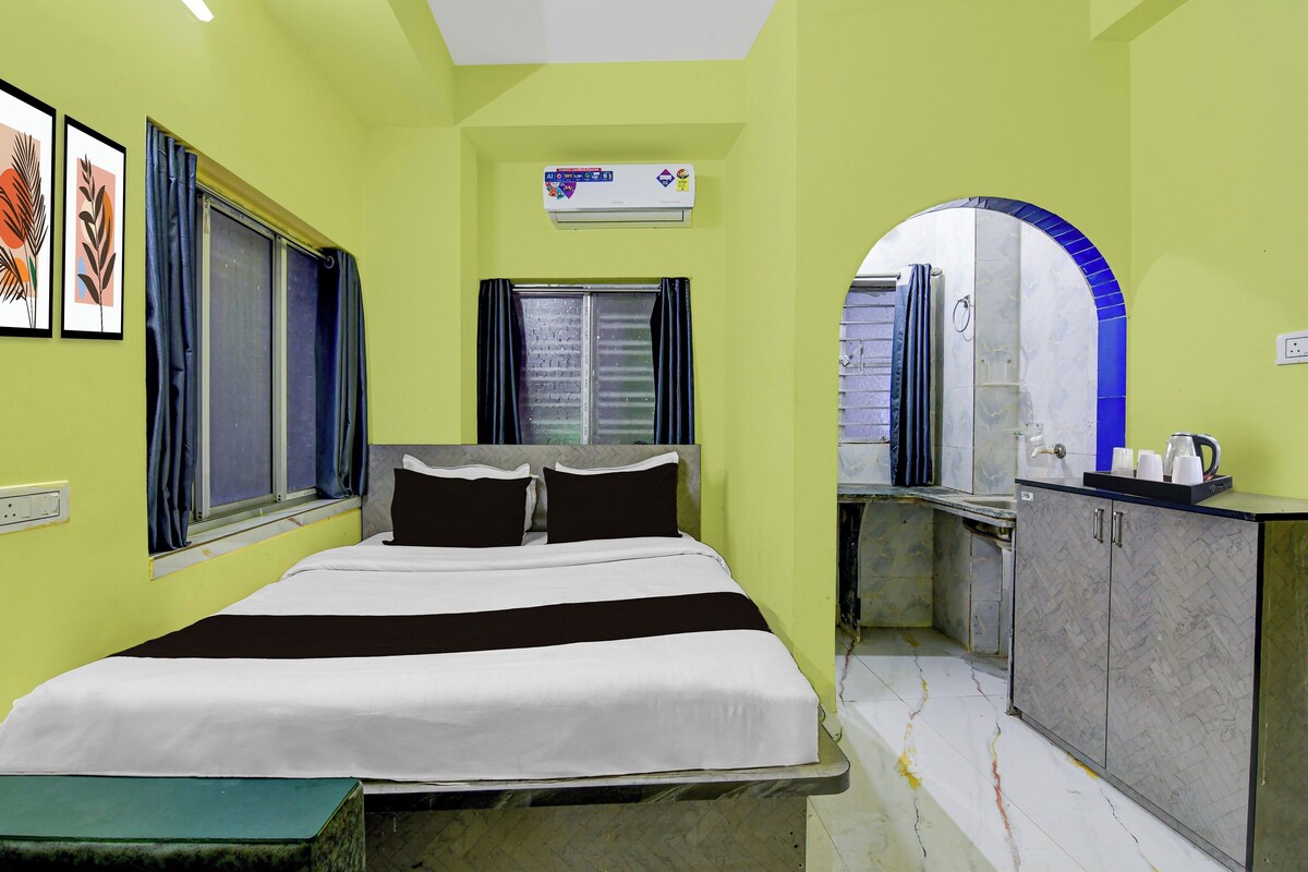 A room with a bed, a window, a bathroom with a mirror, and a sink.