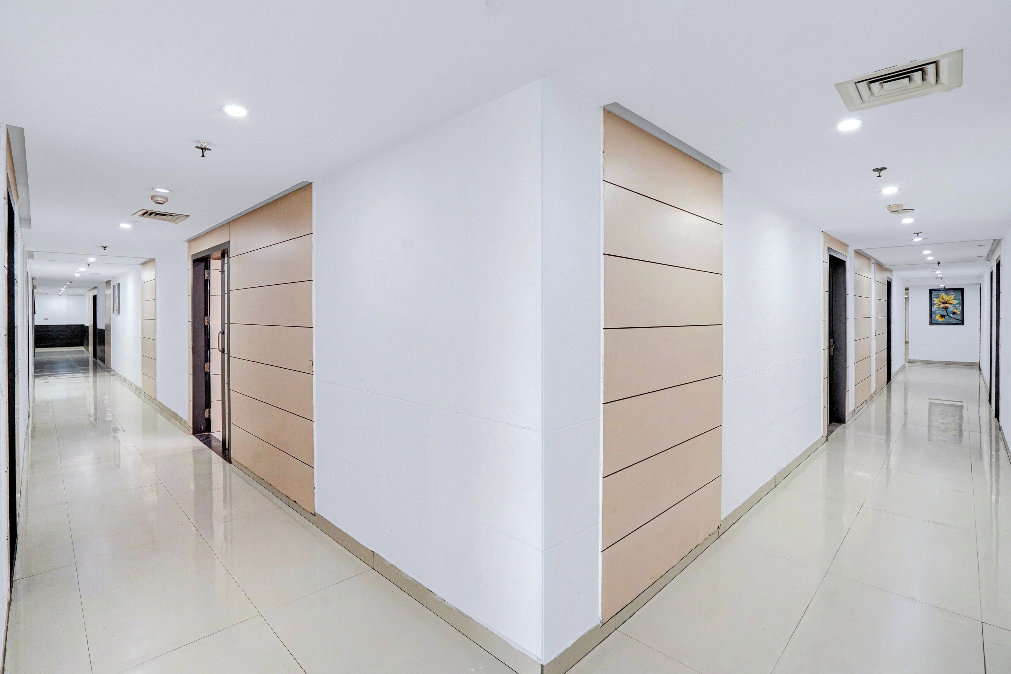 Un largo pasillo bien iluminado con puertas a ambos lados, que conduce a varias habitaciones.