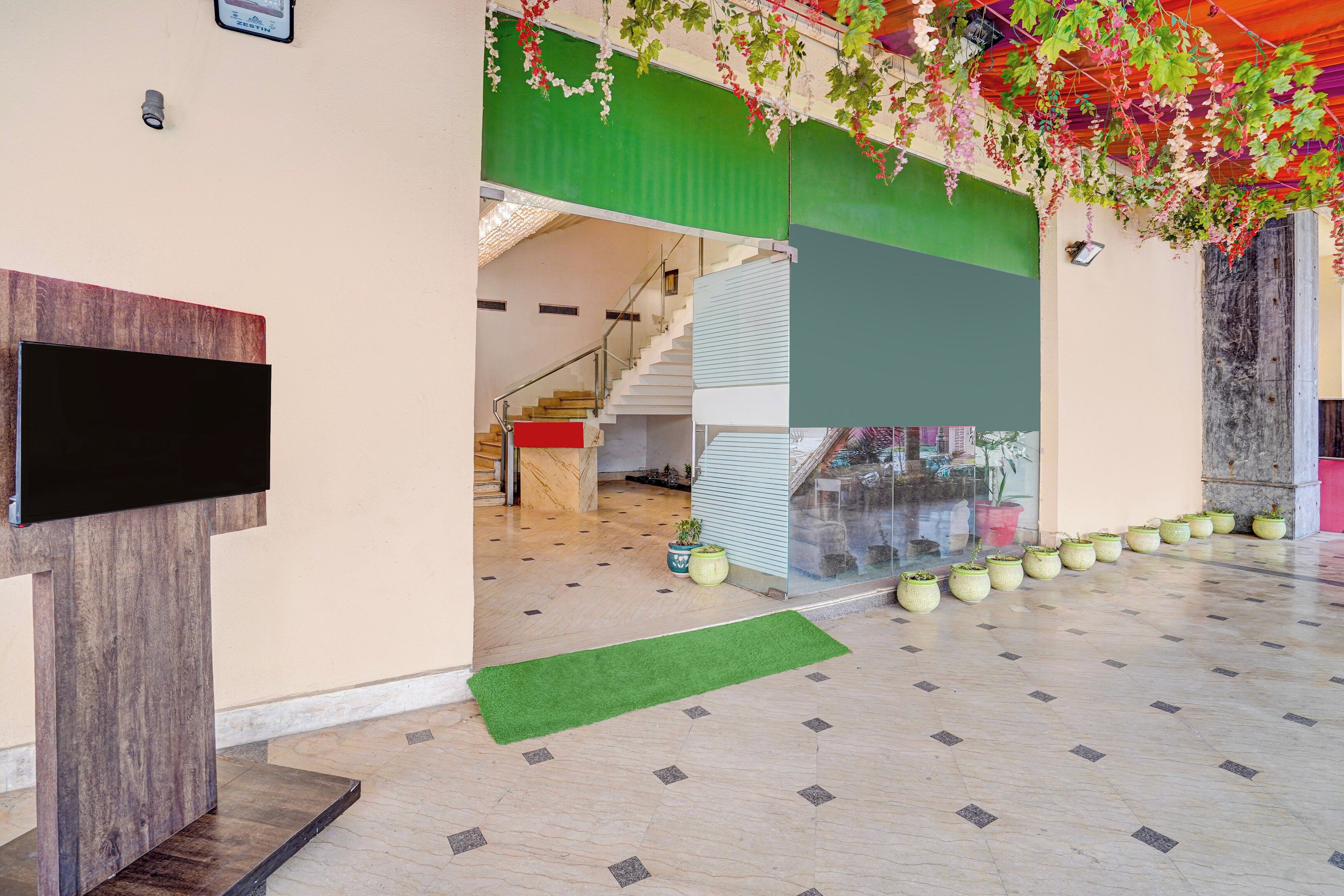 Un interior moderno con una escalera, un televisor de pantalla plana y plantas en macetas.