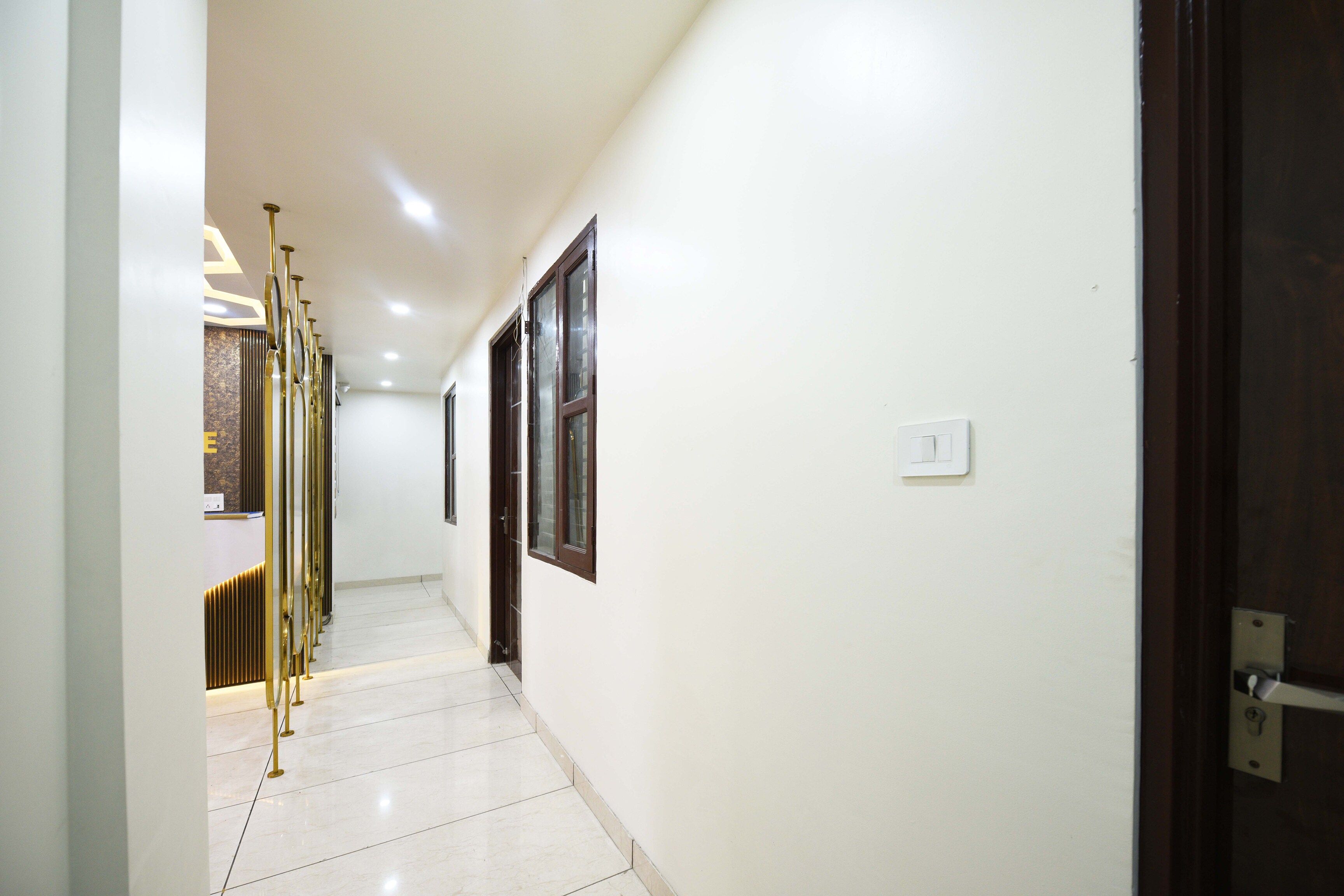 A corridor with a tiled floor, a door on the right, and a wall-mounted light switch.