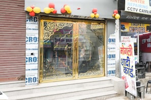 Une devanture de magasin avec une grande porte vitrée ornée de motifs complexes, entourée de divers panneaux et publicités.