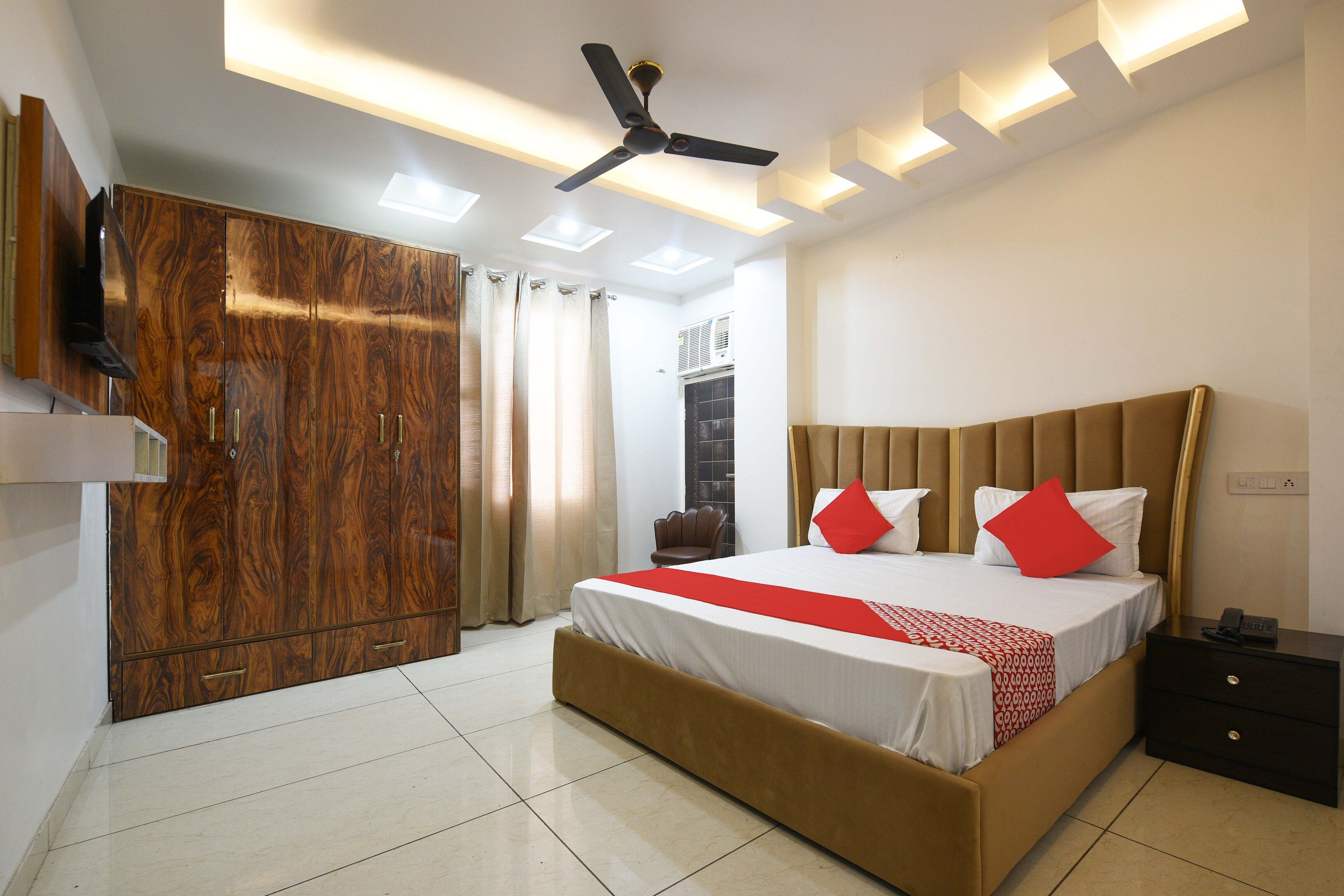 A hotel room with a bed, a wardrobe, a desk, and a ceiling fan.