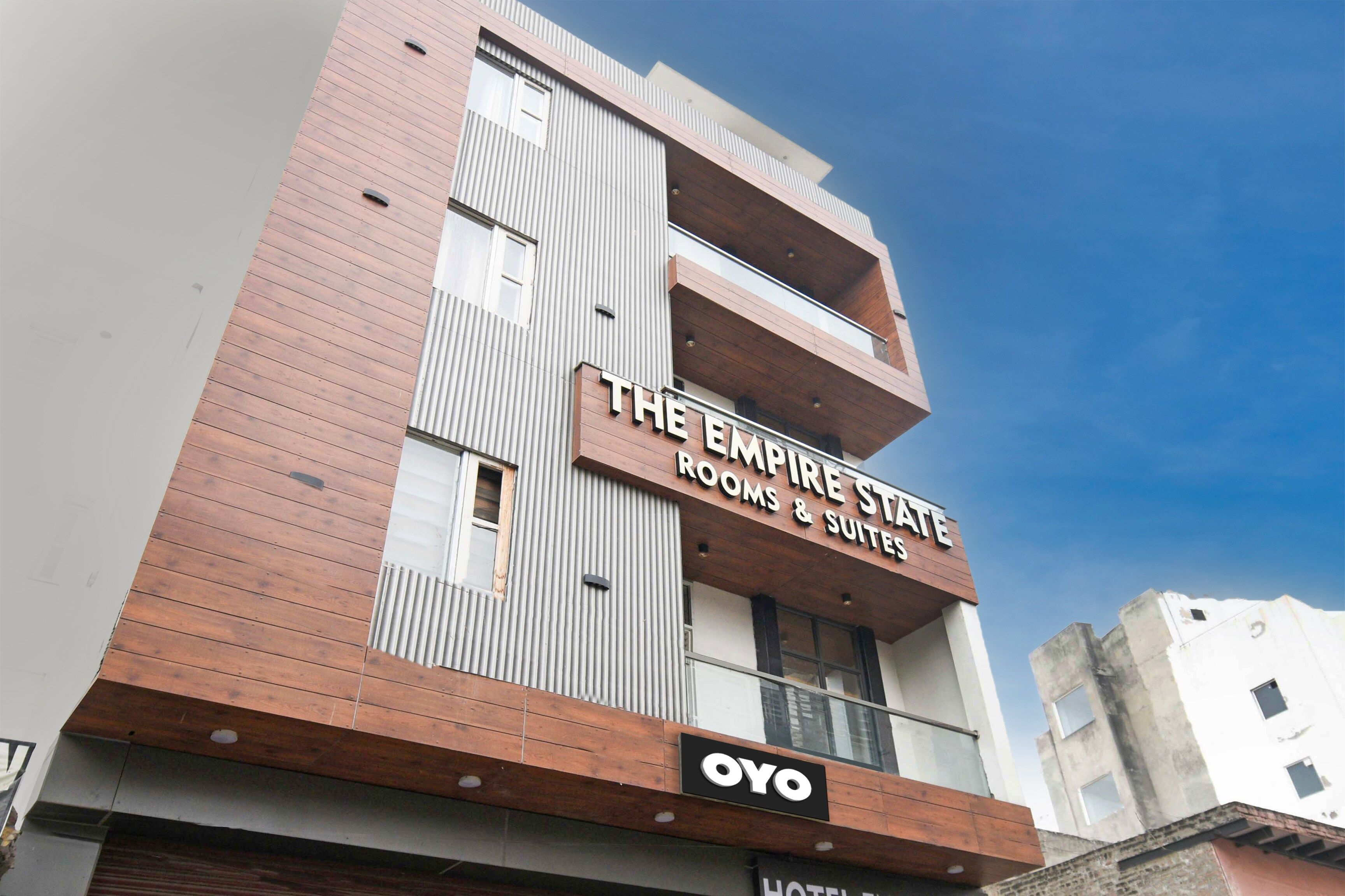 Un edificio de varios pisos con un letrero que dice 'The Empire State Rooms & Suites' y la marca 'OYO'.