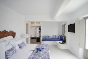 Un dormitorio con cama, zona de estar, armario y televisor.