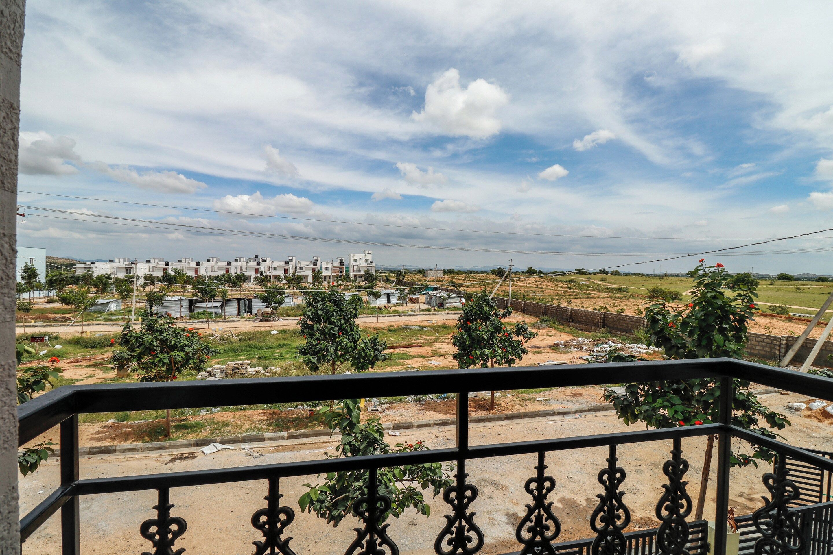 A balcony with a view of a residential area, including houses and open land.