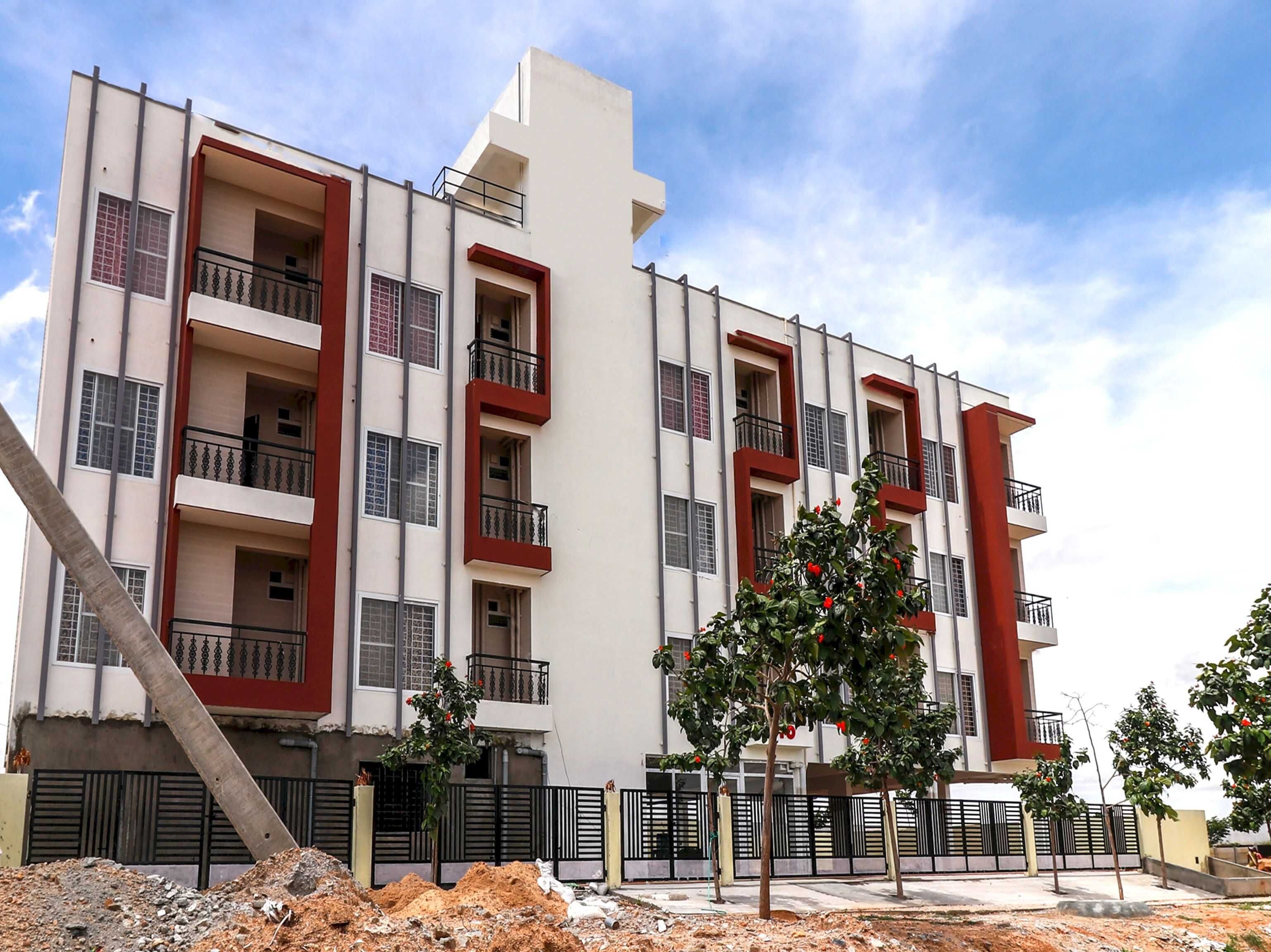 A multi-story residential building with balconies, a gated entrance, and a construction site in the foreground.