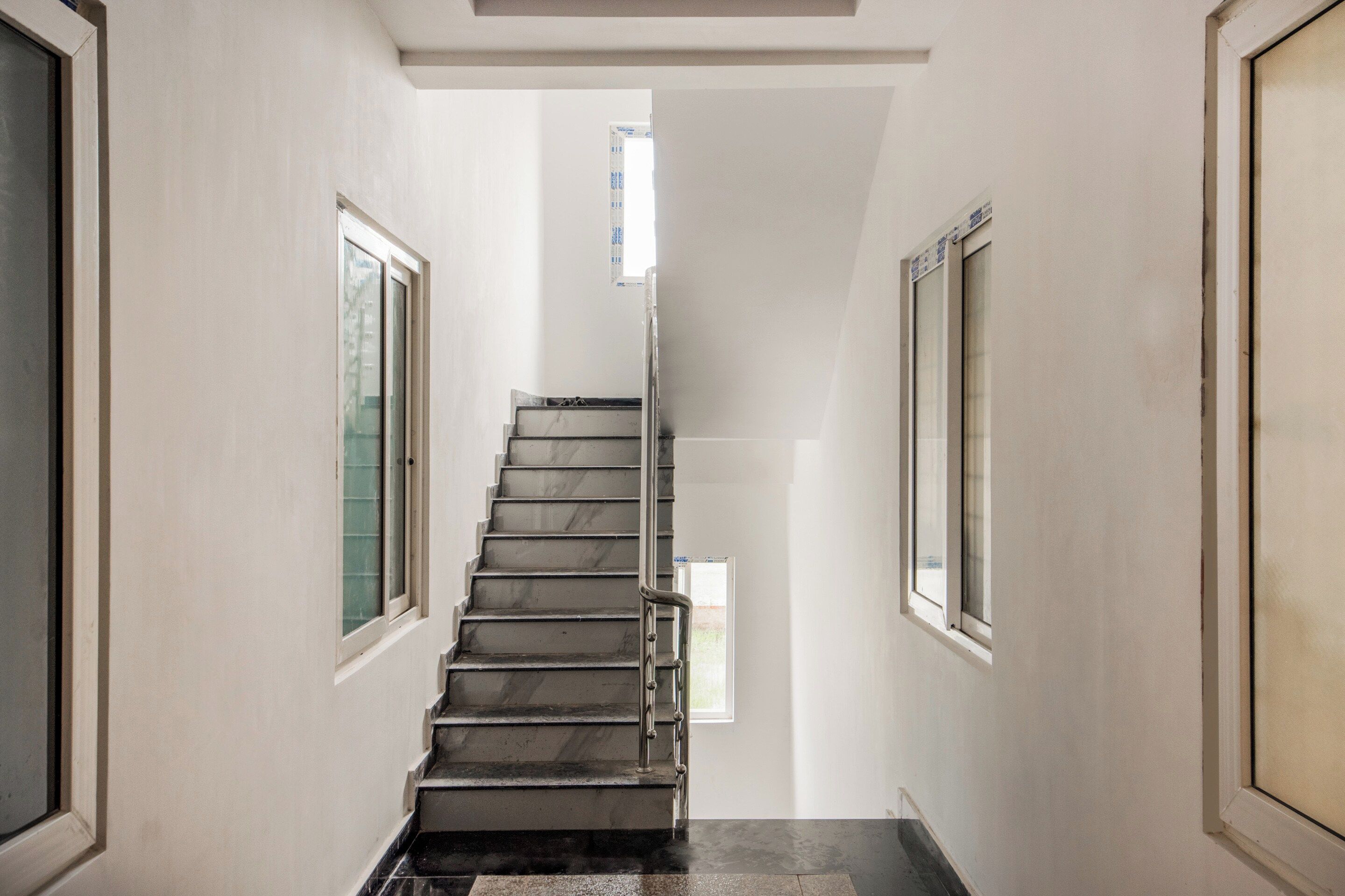 Un pasillo estrecho con una escalera que lleva a una puerta al final.