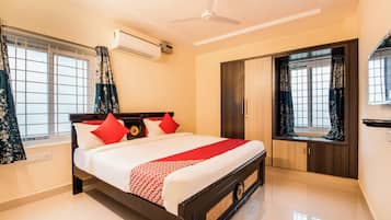 Une chambre d’hôtel avec un lit, un ventilateur de plafond, une fenêtre avec des rideaux et une armoire.