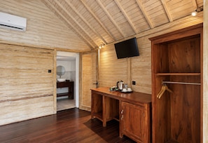 Un interior de madera con una televisión de pantalla plana montada en la pared, un escritorio de madera con un hervidor y un armario de madera.