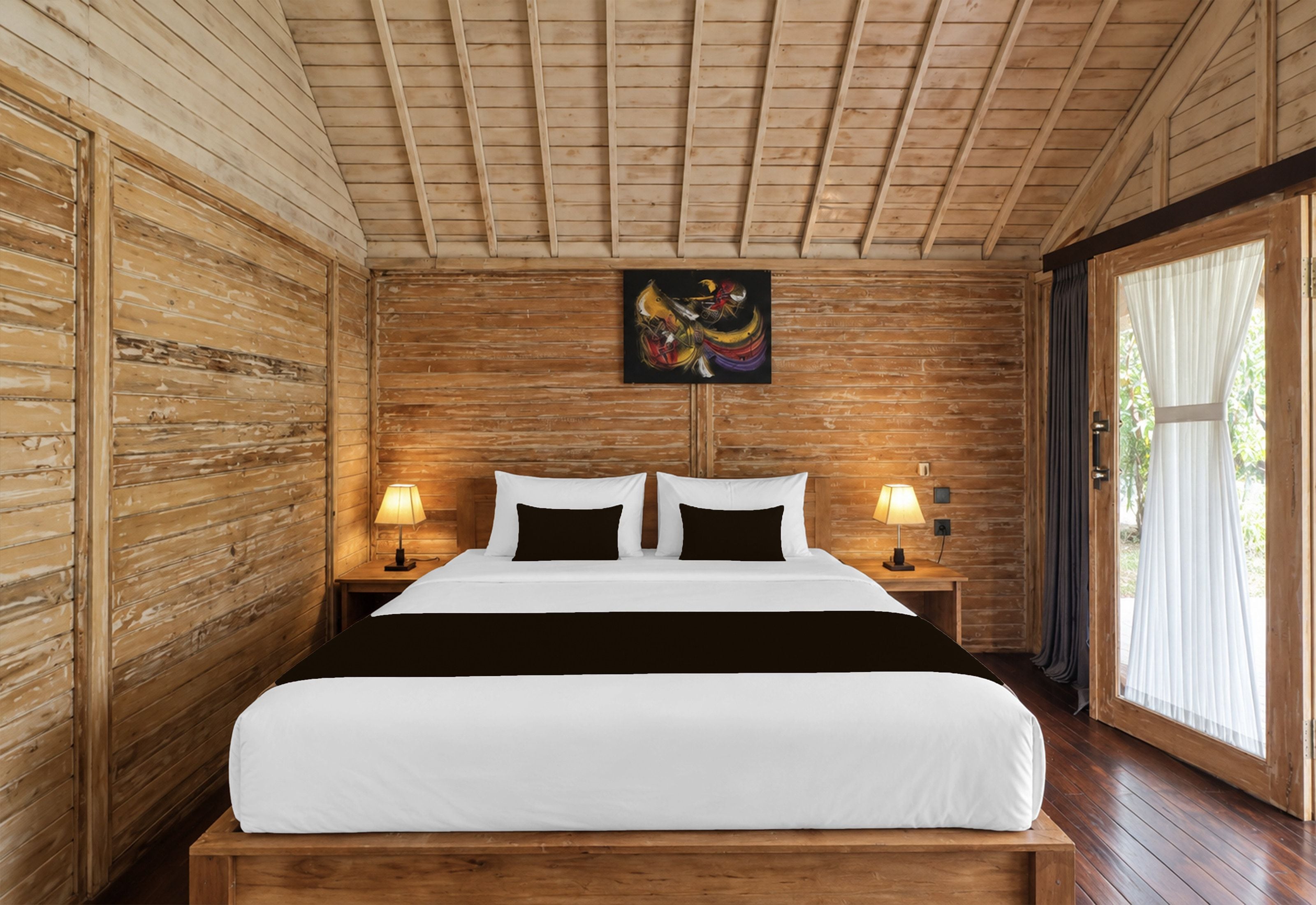 Una habitación con piso de madera, una cama, dos lámparas de noche y un cuadro en la pared.