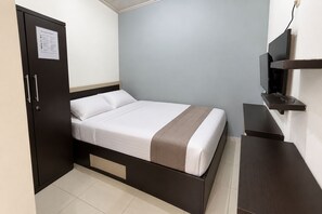 A single bed with a headboard, a wardrobe, a television mounted on the wall, and a small table. - Belvilla Bhavana Cottage (Bali)