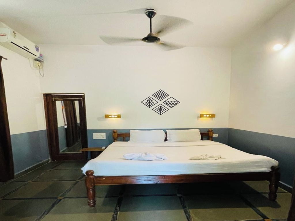 Une chambre d’hôtel avec un lit, un ventilateur de plafond et des lampes fixées au mur.