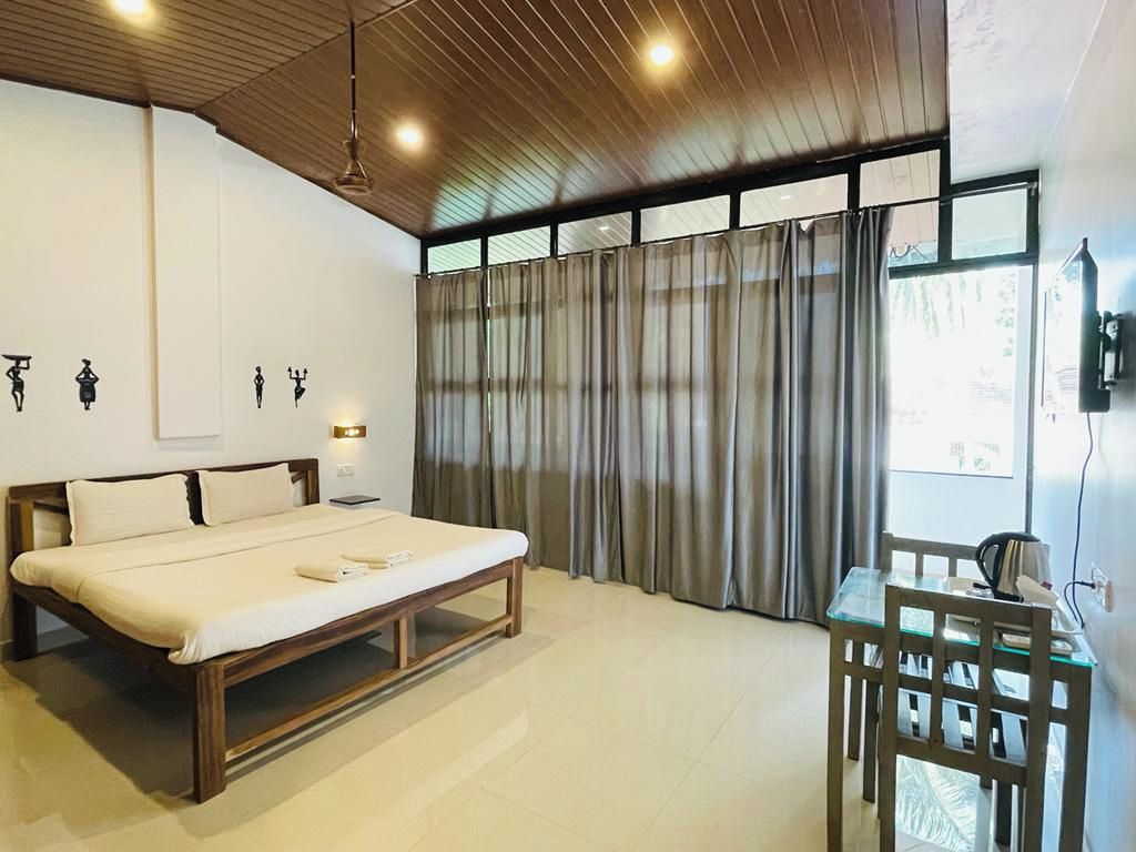 Un dormitorio con cama, escritorio y cortinas.