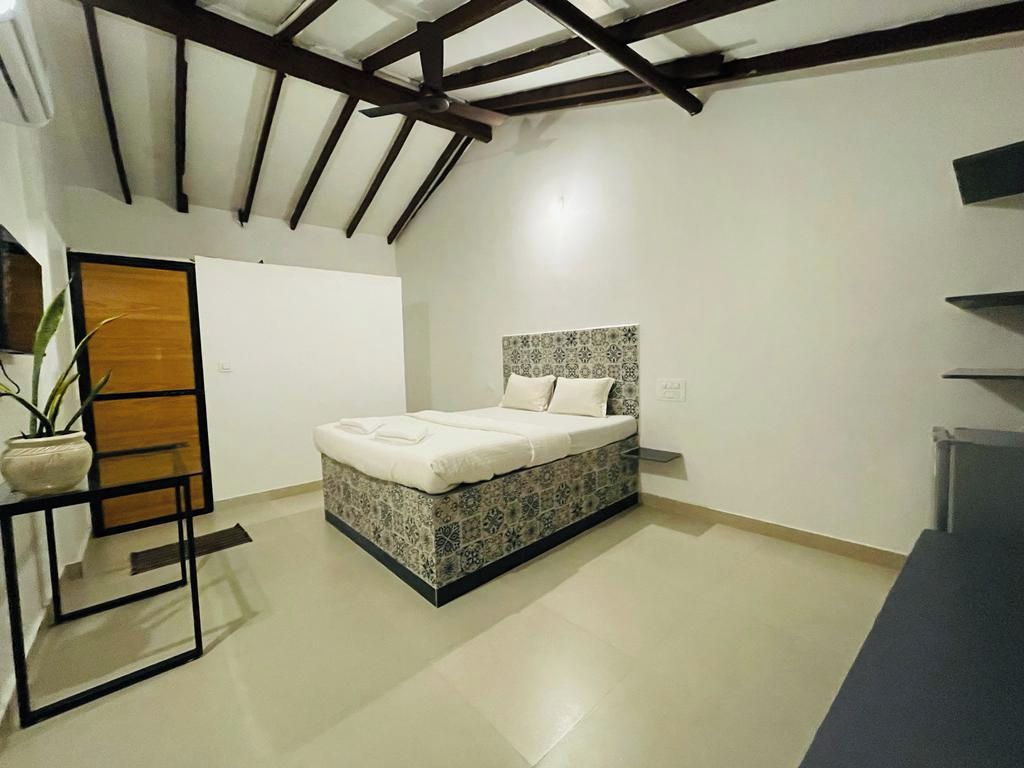Un dormitorio con una cama, una mesita de noche, una planta en maceta y una puerta de madera.