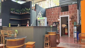 Un espace extérieur aménagé avec des tables et des chaises en bois, un comptoir de bar et un mur en briques.