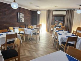 Un comedor con varias mesas y sillas, una pared de ladrillo y una chimenea.