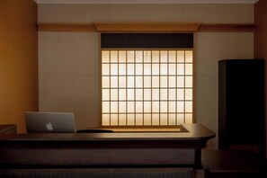 Una habitación con un escritorio de madera, una computadora portátil y una pantalla tradicional japonesa shoji.