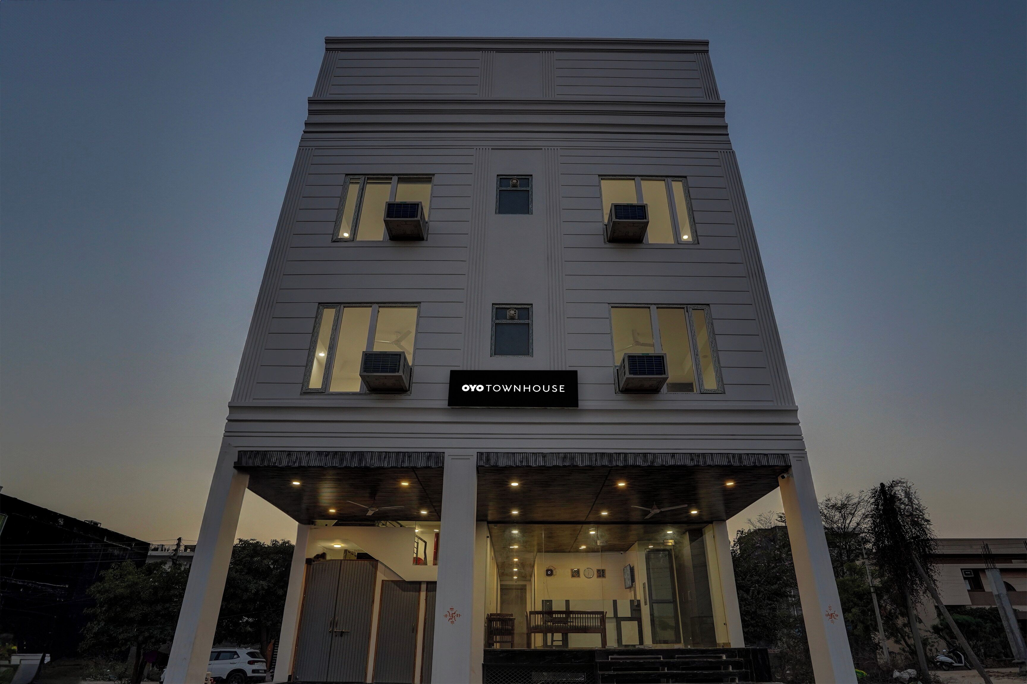 Un edificio de varios pisos con una entrada central y un letrero que dice 'OYO TOWNHOUSE'.