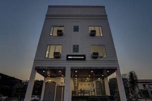 Un edificio de varios pisos con una entrada central y un letrero que dice 'OYO TOWNHOUSE'.