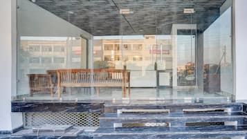 Un edificio moderno con fachada de vidrio, un banco de madera y una escalera que lleva a una entrada.