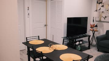 Un comedor con una mesa, sillas, un televisor y un sofá.