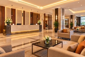 A modern hotel lobby with a reception desk, seating area, and large windows. - Hotel TwentyFour Grandeur (Perundurai)