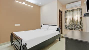 Une chambre à coucher avec un lit, un bureau, un climatiseur et une fenêtre avec des rideaux.
