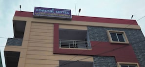 Un edificio de varios pisos con un letrero que anuncia Coastal Suites, indicando habitaciones con y sin aire acondicionado.