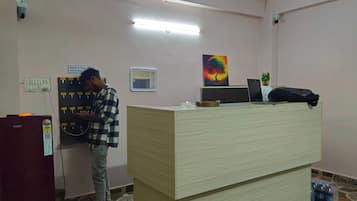 Un espace d’accueil comprenant un comptoir d’enregistrement, un ordinateur et un réfrigérateur de la marque Haier.