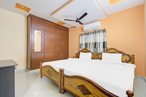 A bedroom with a wooden bed, a wardrobe, a ceiling fan, and an air conditioning unit. - Hotel O Sea Coastal (Kakinada)
