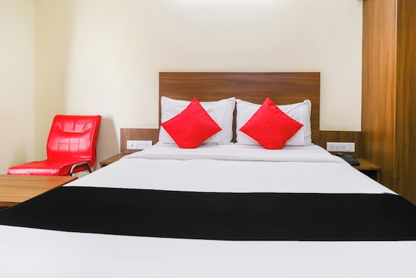 Una habitación de hotel con una cama, una silla roja y un cabecero de madera.