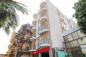 Un edificio de varios pisos con balcones, un toldo rojo y un letrero con un personaje de caricatura.