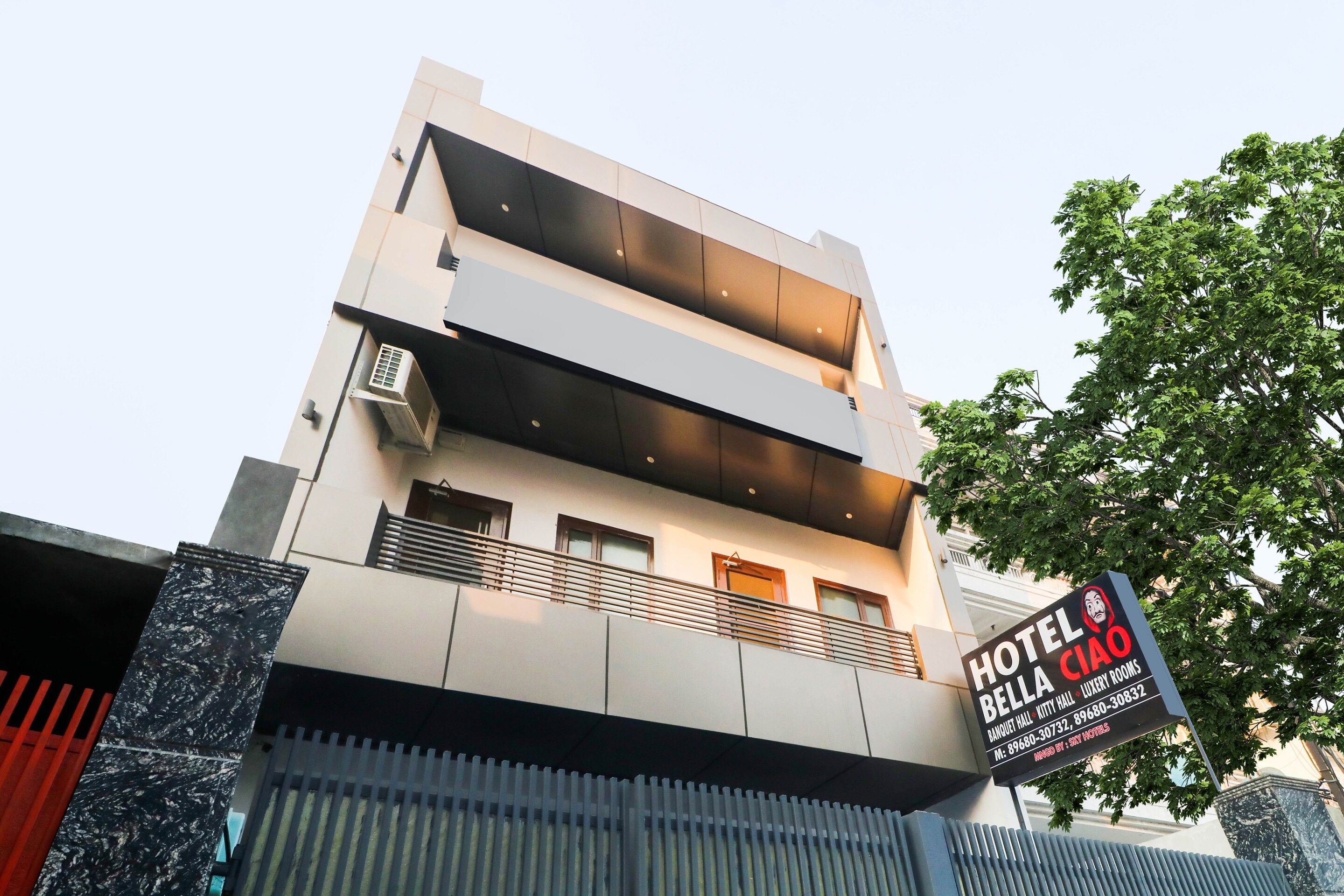 A modern hotel with a signboard indicating 'HOTEL BELL Ciao' and contact details.