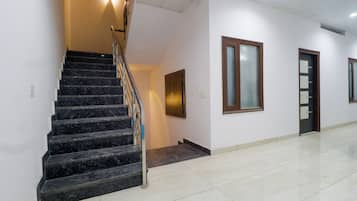 A staircase with a handrail leading to a landing, a door with a frosted glass panel, and a wall-mounted light fixture.