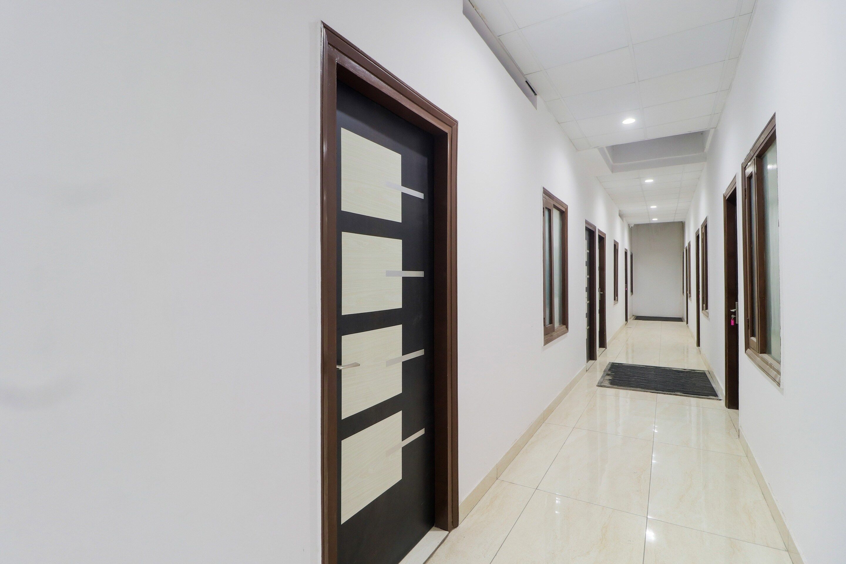 A corridor with doors, a tiled floor, and a ceiling with recessed lighting.
