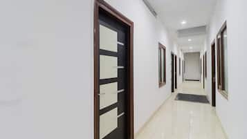 A corridor with doors, a tiled floor, and a ceiling with recessed lighting.