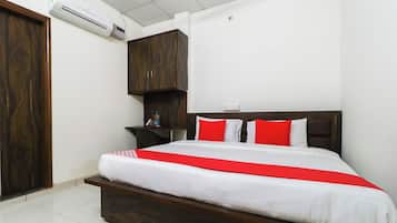 Una habitación de hotel con una cama de madera, ropa de cama blanca y detalles en rojo.