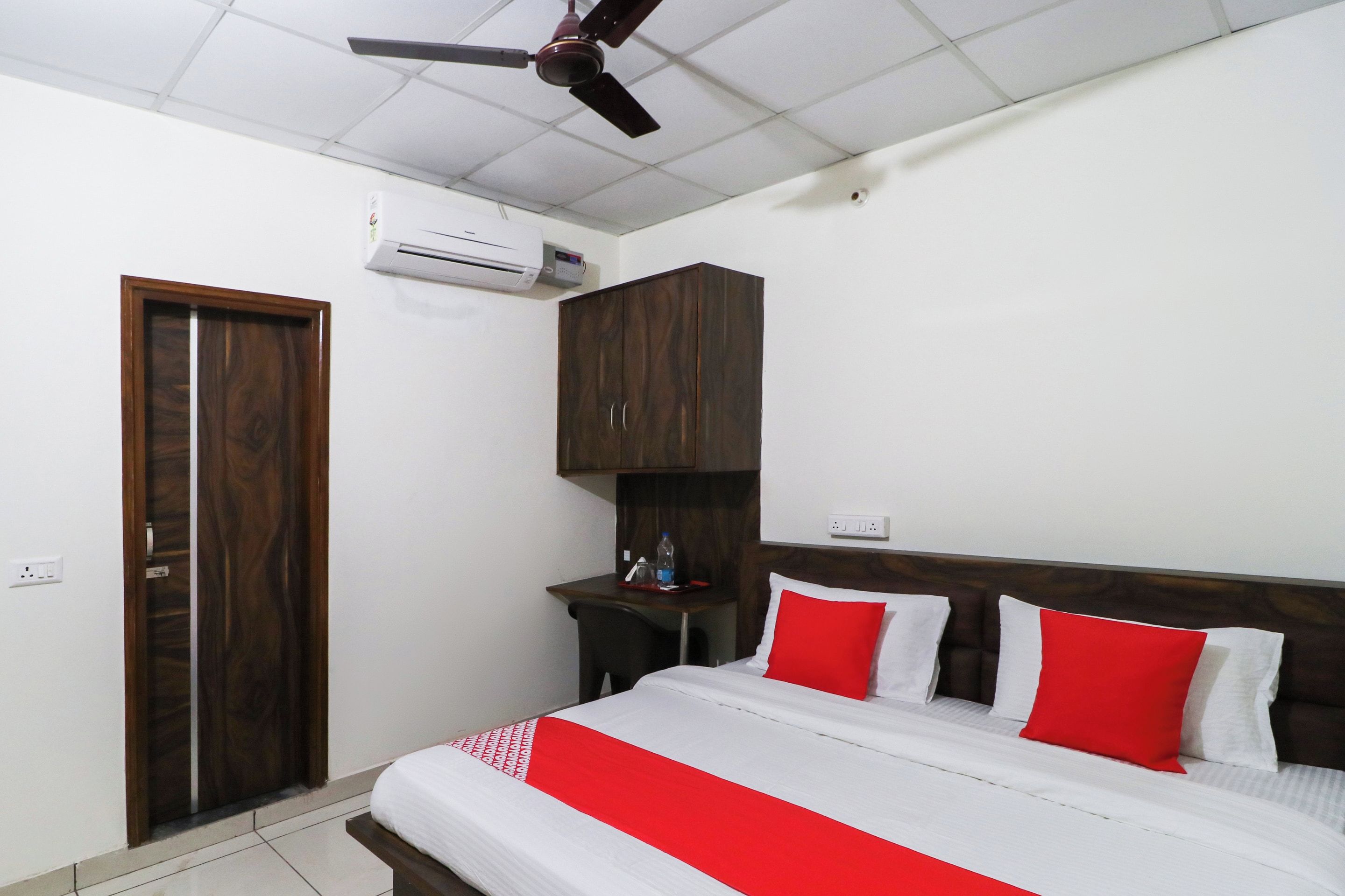 Un dormitorio con cama, armario, escritorio y ventilador de techo.