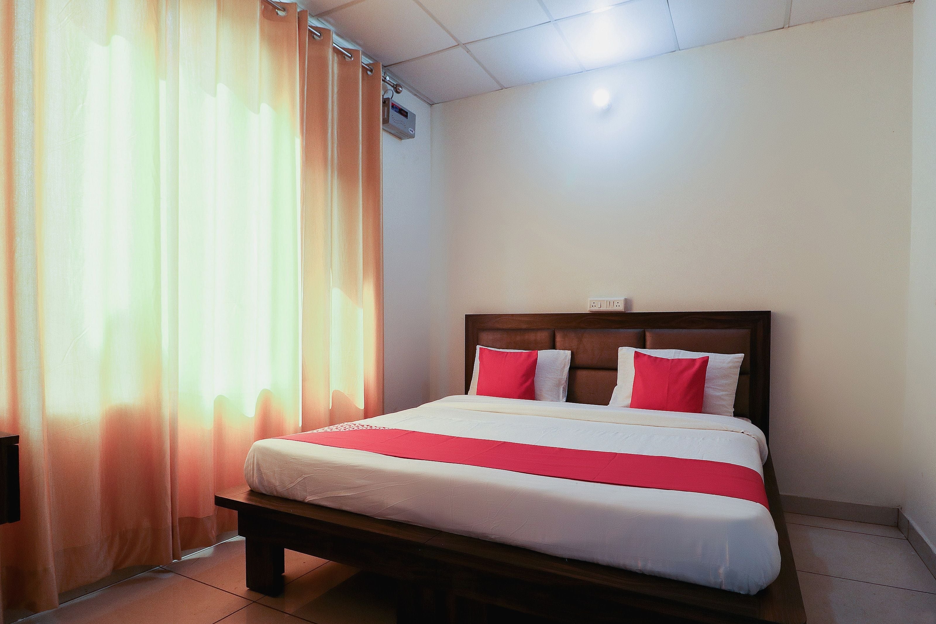 Une chambre d’hôtel avec un lit, des rideaux et un climatiseur fixé au mur.