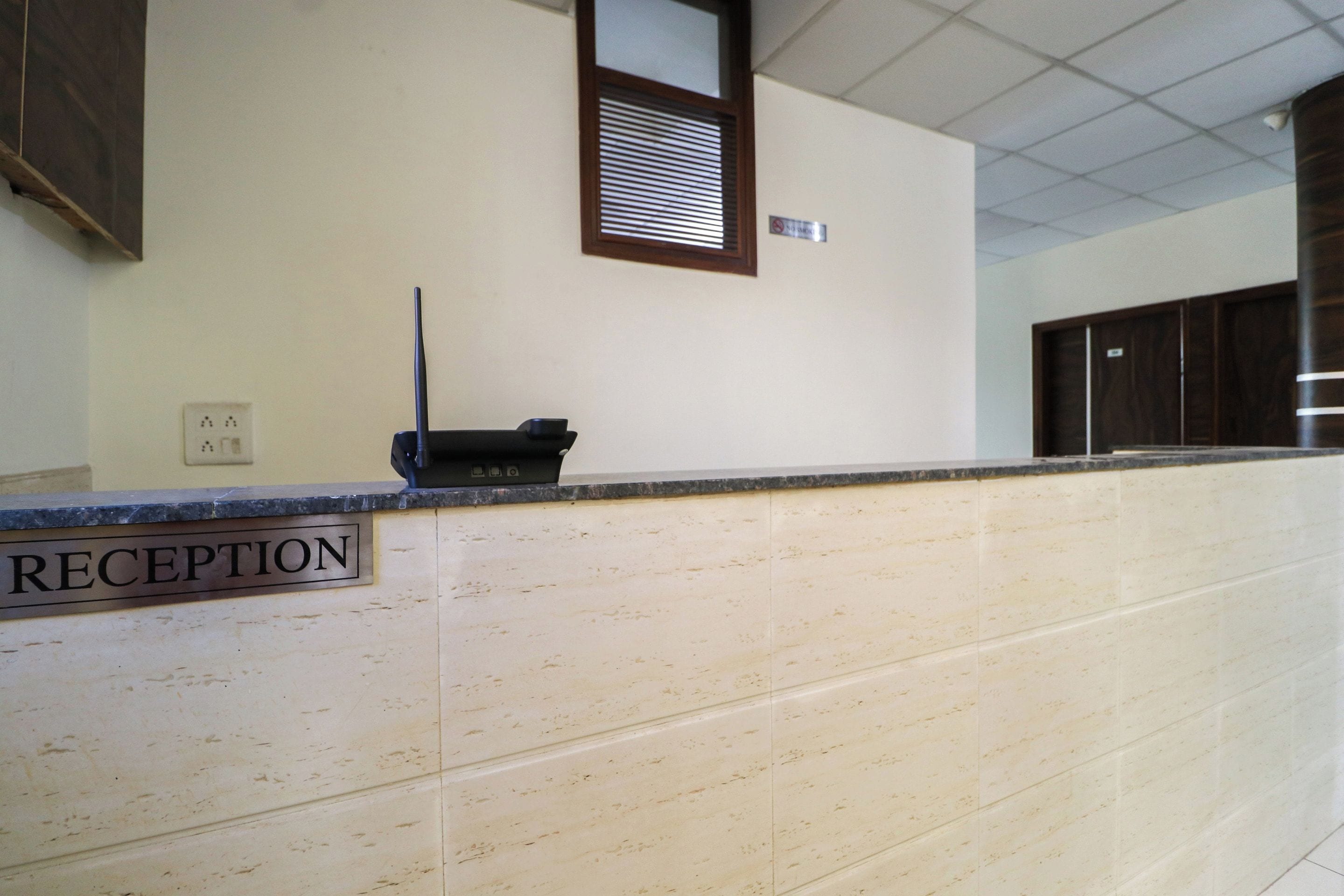 Un mostrador de recepción con un cartel que dice 'RECEPTION' y un portero automático instalado en la pared.