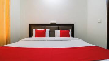 A bed with a white and red bedspread, two red pillows, and a dark headboard.