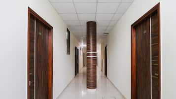 Un pasillo con puertas de madera a ambos lados, un pilar central y piso de baldosas.