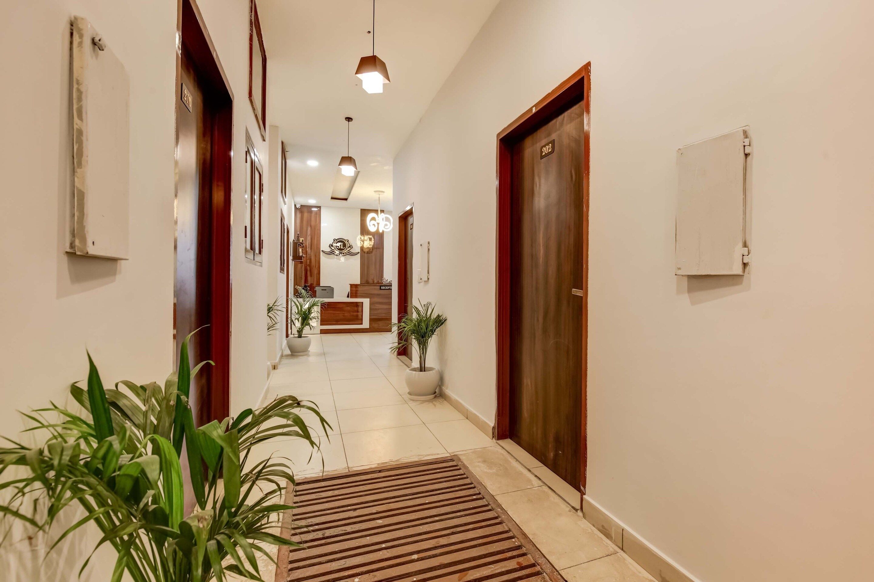 A hotel hallway with a reception desk, potted plants, and a reception area.